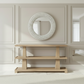 Wooden console table with decorative mirror in a room with light-colored walls and flooring.