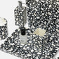 Bathroom set with black and white terrazzo pattern including soap dispenser, toothbrush holder, and bottle.