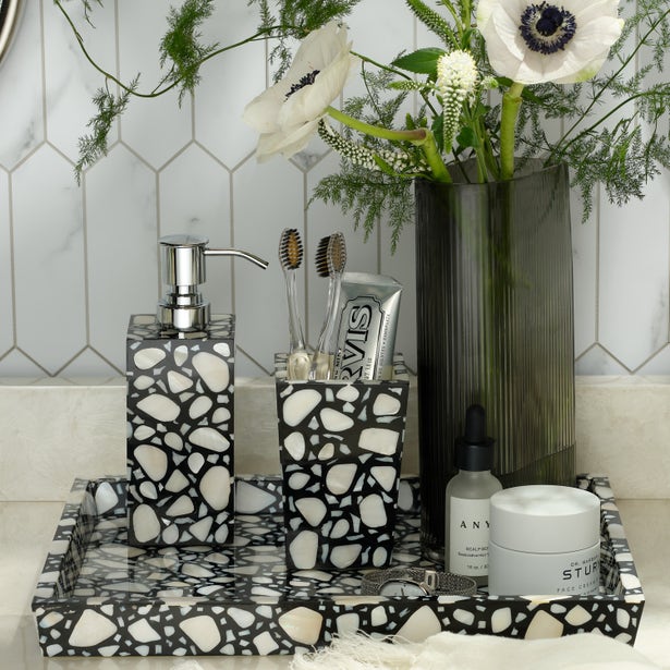 Bathroom setting with decorative soap dispenser, toothbrush holder, and floral arrangement.