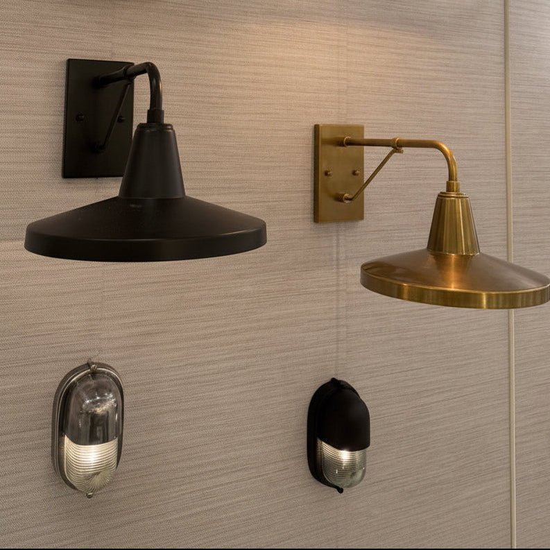 Four industrial-style wall sconces mounted on a light beige textured wall, including two black and two brass/gold models, some with adjustable arms and one with a rectangular frame.