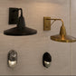 Four industrial-style wall sconces mounted on a light beige textured wall, including two black and two brass/gold models, some with adjustable arms and one with a rectangular frame.