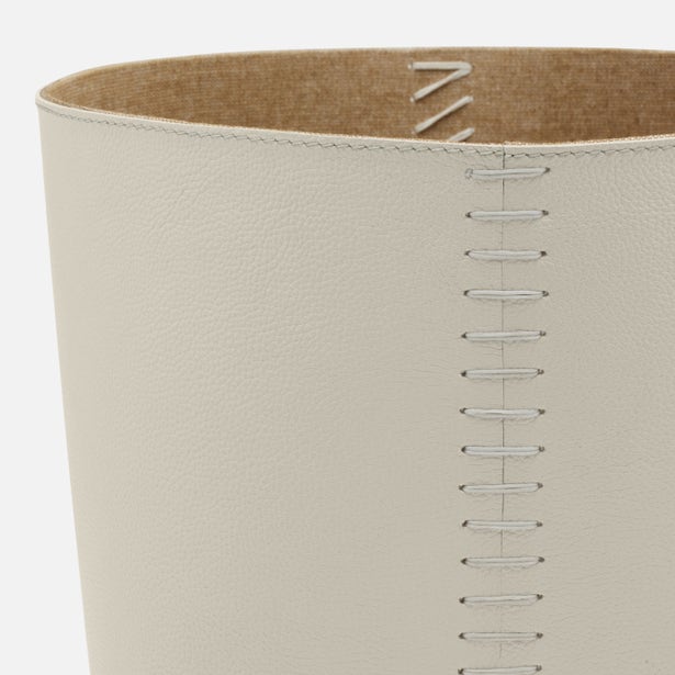 Close-up of a beige leather product with stitching details on a white background