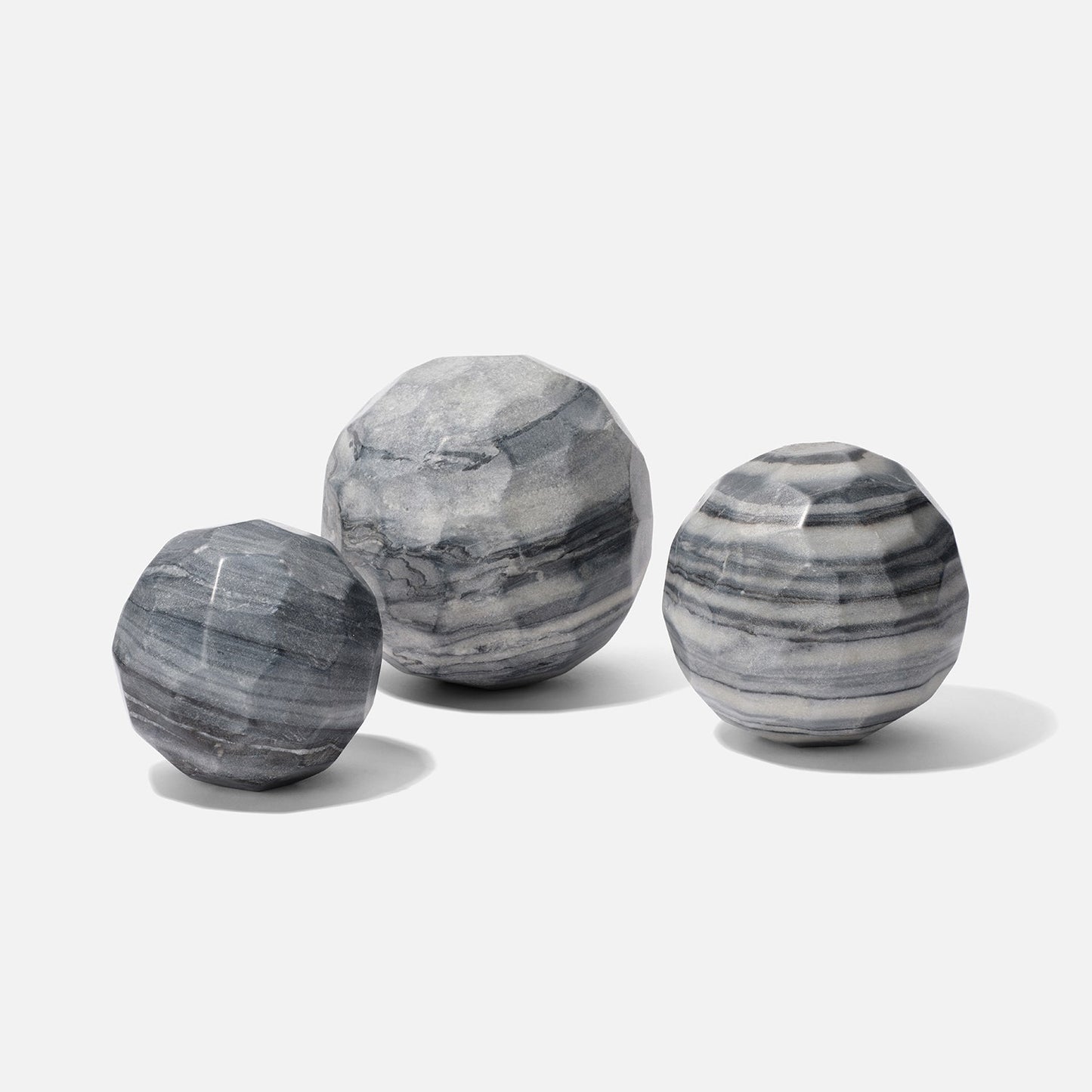 Three gray marble spheres of different sizes on a white background