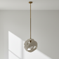 Ceiling light fixture hanging in a room with a window casting shadows on the wall.