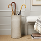 Concrete umbrella stand holding three umbrellas against a neutral wall.