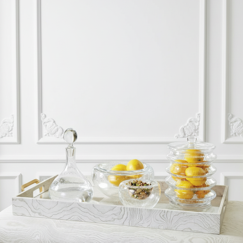 Decorative table setting with lemons and a decanter against a white paneled wall.