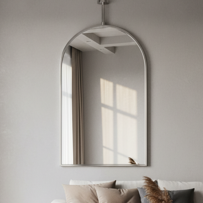 Modern living room with a white sofa, decorative pillows, and a mirror on the wall.