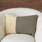 Decorative pillow with beige and black striped pattern on a white armchair.