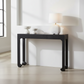 Black console table with white lamp and decorative items against a white wall.