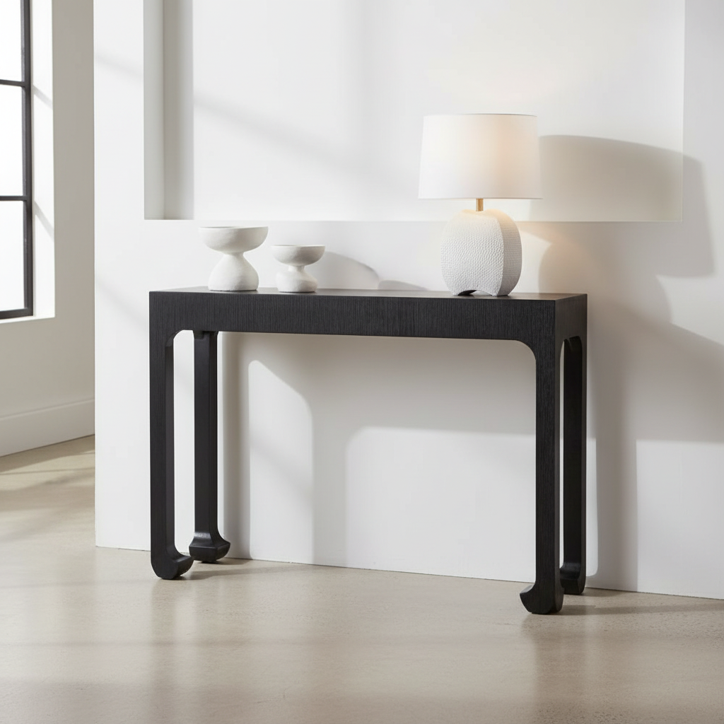 Black console table with white lamp and decorative items against a white wall.