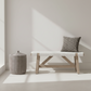 Minimalist interior with a bench and woven basket against a white wall. (drip pillow and wentworth bench)