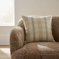 Brown textured armchair with a plaid cushion in a room with a window.