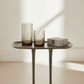 Two textured glass tumblers on a small round table with a light background