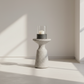 Cylindrical candle holder with a candle on a light wooden floor with soft shadows