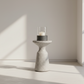 Cylindrical candle holder with a candle on a light wooden floor with soft shadows