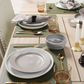 Elegant table setting with plates, bowls, candles, and apples on a wooden table.