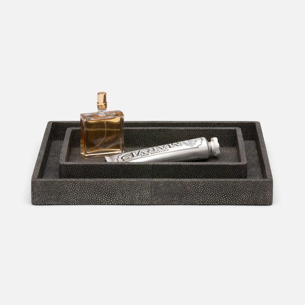 Black shagreen tray with a perfume bottle and tube on a white background