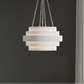 Modern pendant light hanging against a dark wall with a window in the background