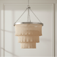 Chandelier with beige mesh design hanging against a neutral wall.