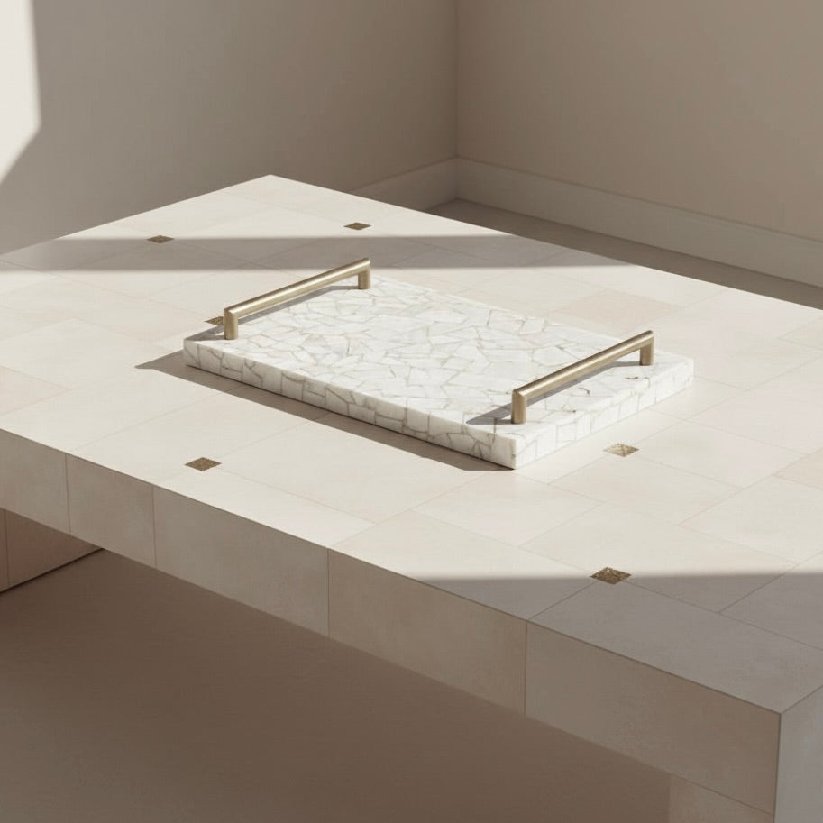 Marble tray with gold handle on a light-colored surface. madelyn
