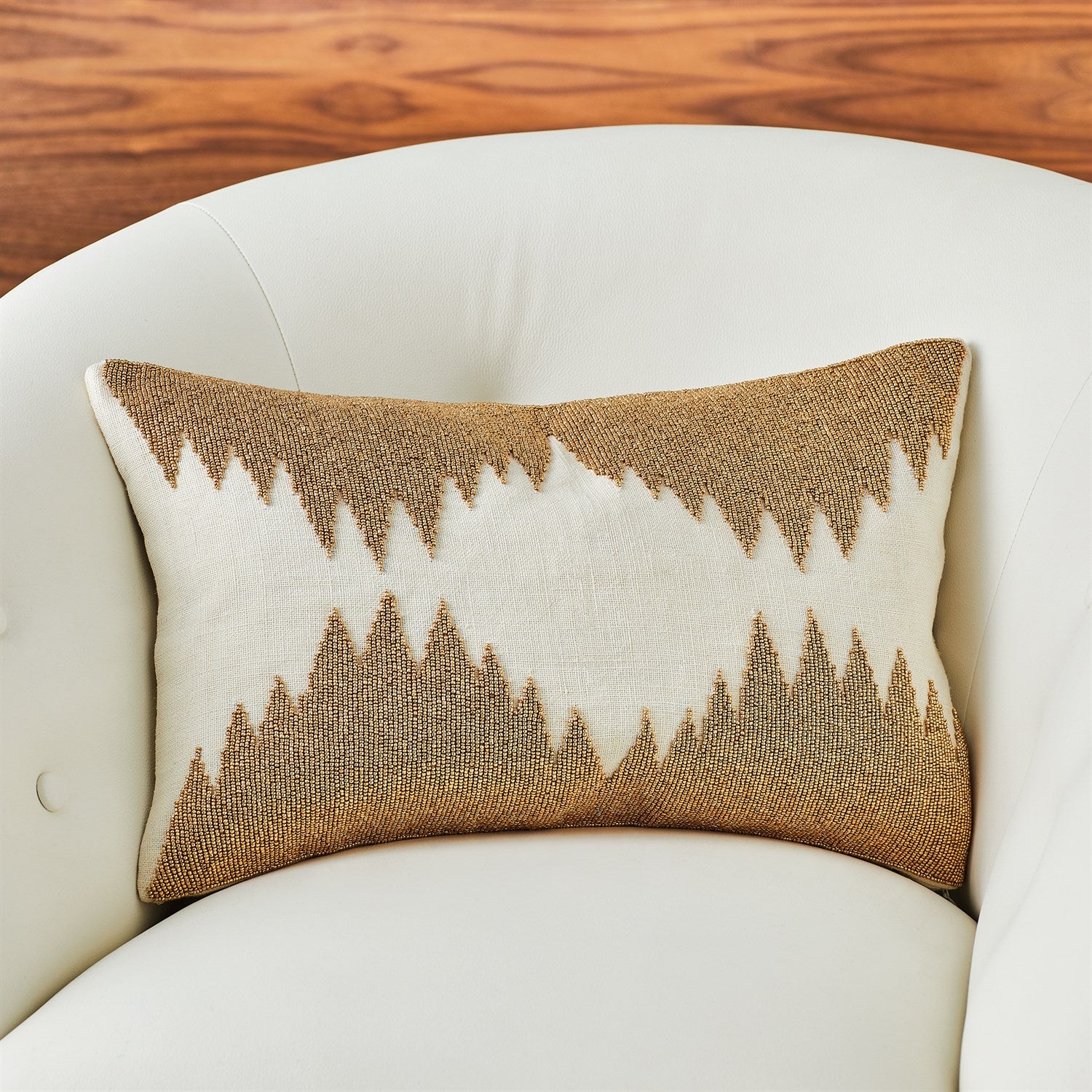 Decorative pillow with a geometric pattern on a white armchair against a wooden background