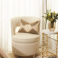 Beige armchair with a decorative pillow next to a gold side table with a vase of flowers.