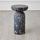 Marble side table with a dark, veined pattern on a wooden floor.