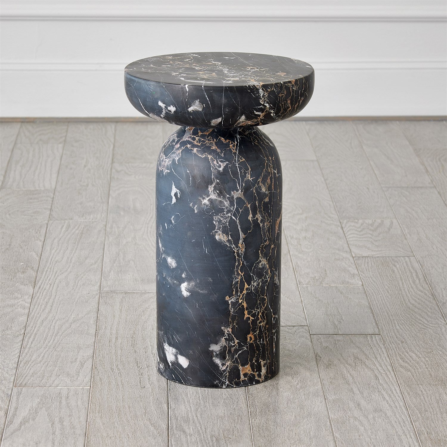 Marble side table with a dark, veined pattern on a wooden floor.