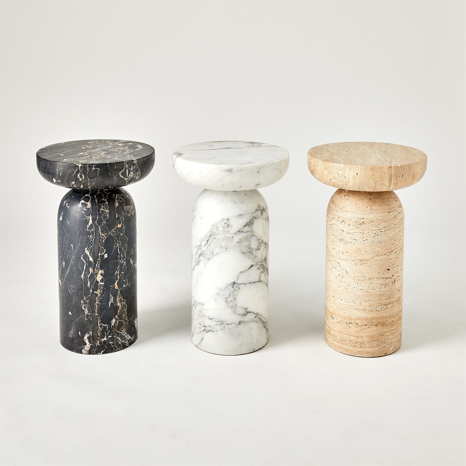 Three marble stools in black, white, and beige on a light gray background