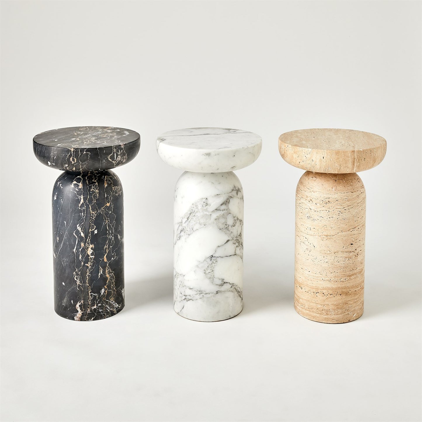 Three marble stools in black, white, and beige on a light gray background