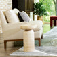 Beige armchair with striped pillow on a rug in a room with a plant and window.