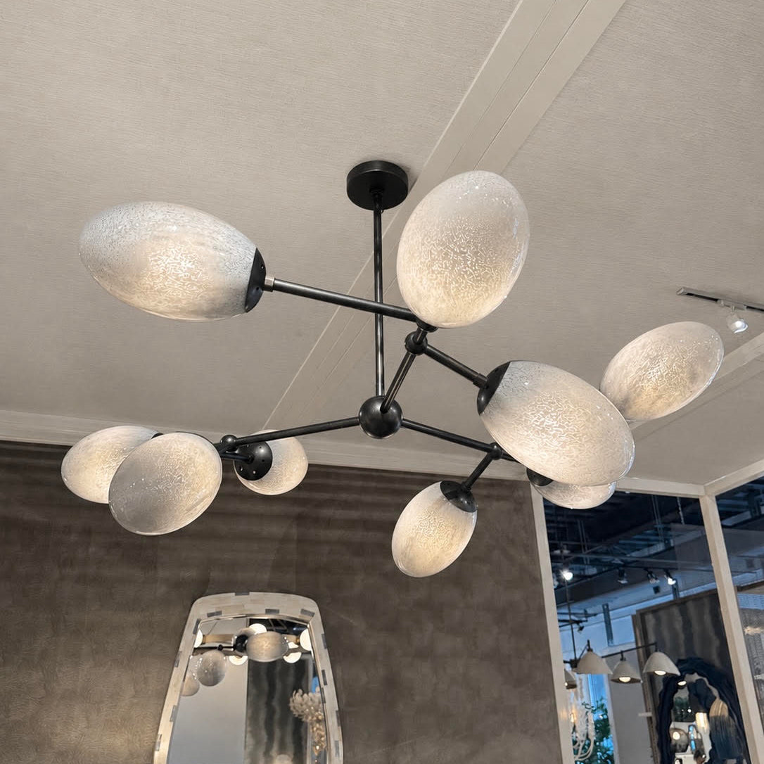 A modern multi-arm ceiling light fixture with textured white glass globes on a black metal frame, shown installed on a ceiling in an interior room.