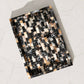 A rectangular tray with a mosaic tile pattern in black, white, and warm brown, photographed from an overhead angle on a light marble surface.