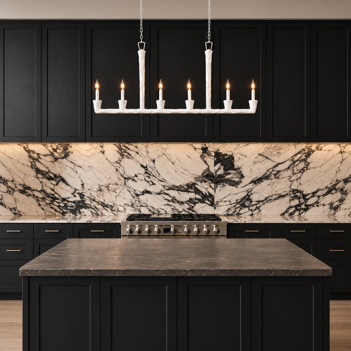 A modern kitchen scene with black cabinets, a white marble backsplash, a dark stone countertop island, and a white multi-light pendant chandelier hanging above the island.