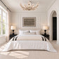 An ivory coconut shell flush mount displayed in an elegant neutral bedroom with white paneled walls, black nightstands, arched doorway, and natural light.