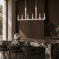 A white candelabra-style pendant chandelier with six candle-shaped bulbs hangs over a dark marble kitchen island in a modern kitchen setting with dark wood cabinetry and bar stools.