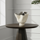 White decorative vase on a dark wooden table against a light gray wall. (demetrius)