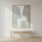 Abstract art piece on a wall above a wooden bench in a minimalistic room.