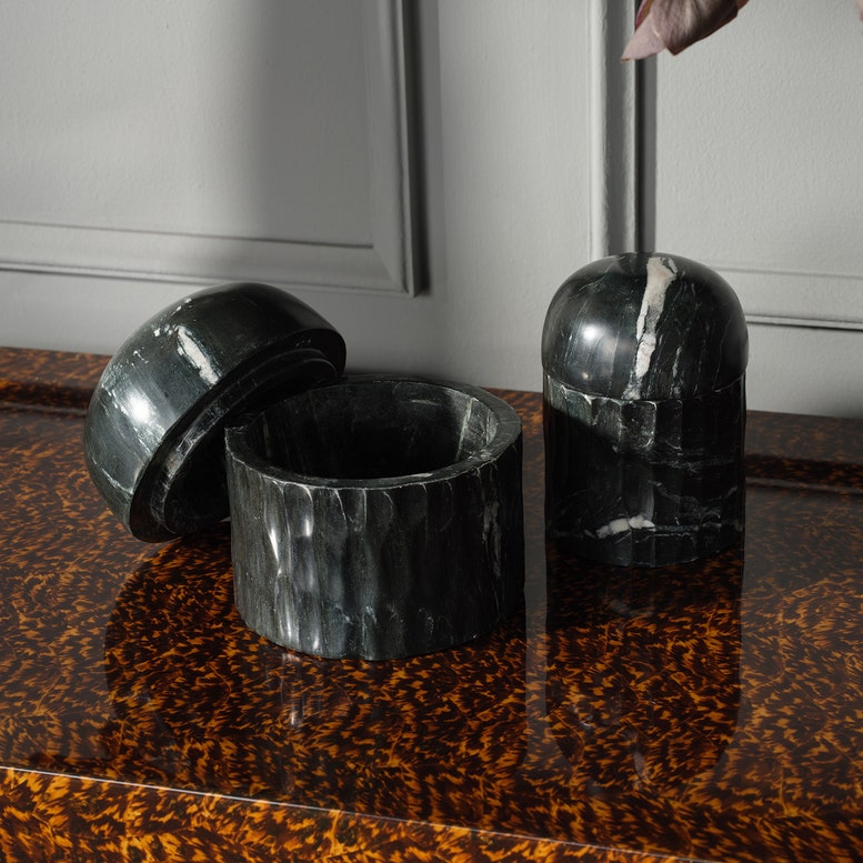 Black marble containers on a wooden surface with a neutral background