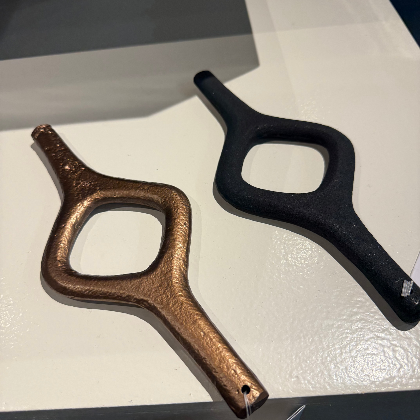 Two hair styling tools, one bronze and one black, on a white surface.