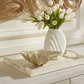 White vase with tulips on a decorative tray in a home setting