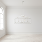 White chandelier hanging in a minimalistic room with white walls and floor.
