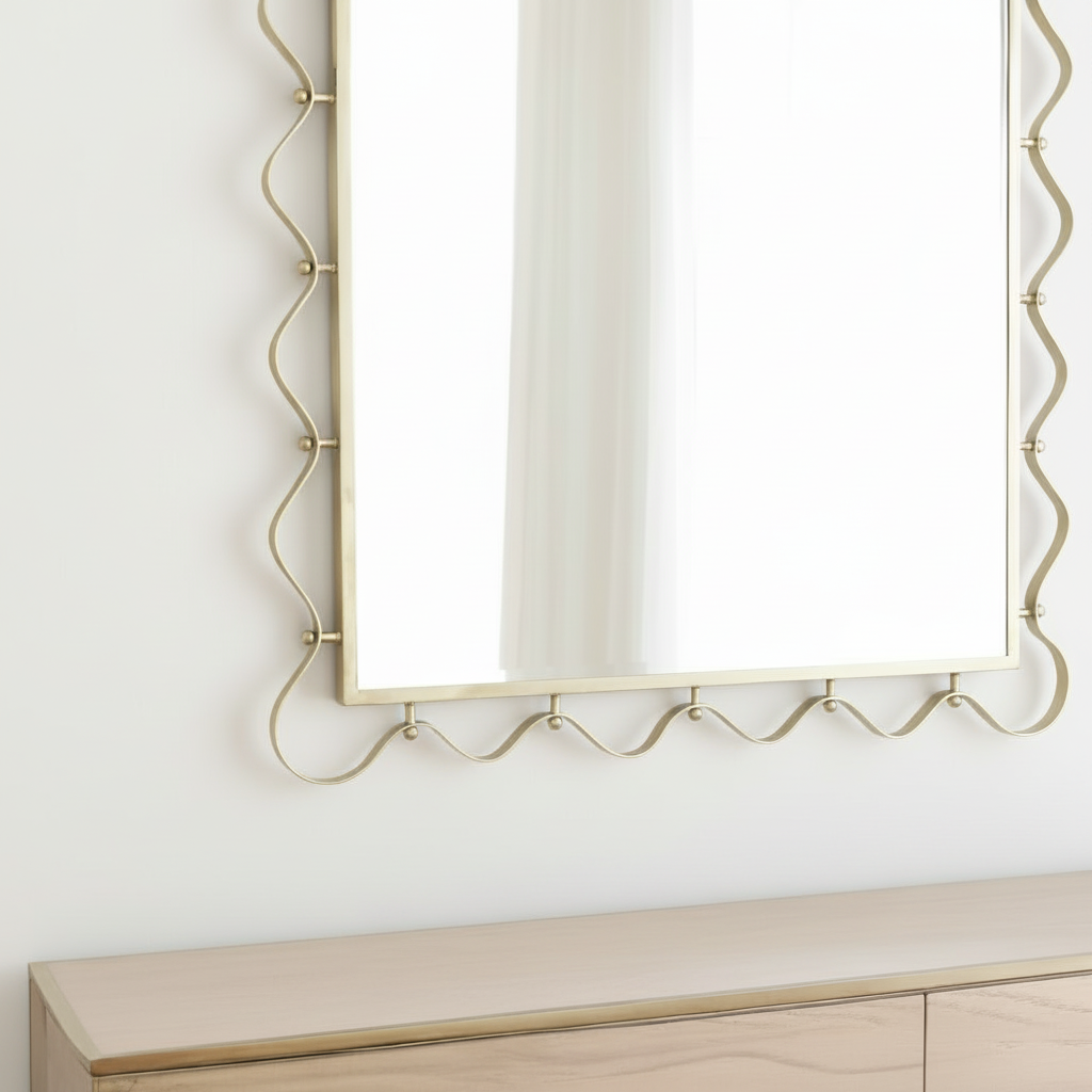 Decorative wall mirror with gold frame on a white wall above a wooden surface