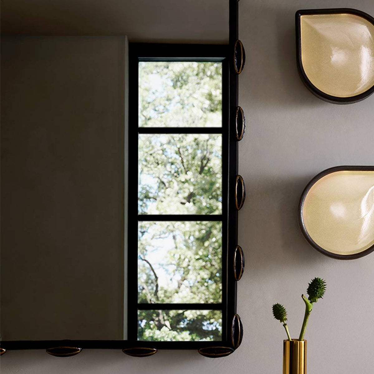 Window with black frame showing greenery outside, wall with ceramic bowls and a vase.
