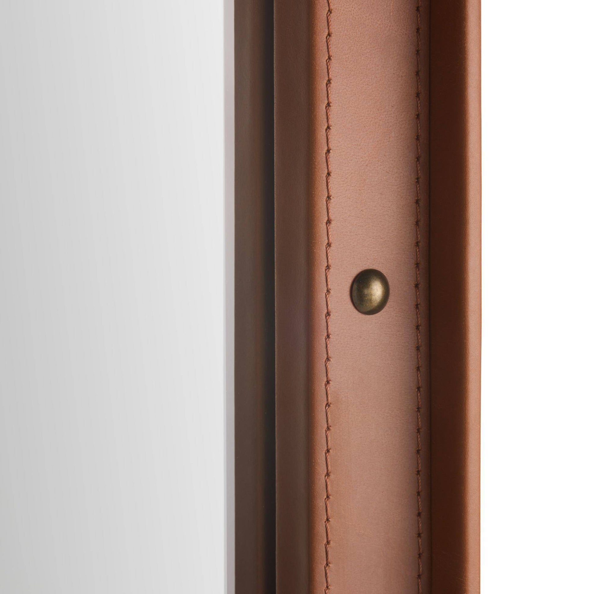 Close-up detail of a brown leather or faux-leather trim piece with visible stitching and a small round brass-toned rivet, set against a white background.