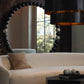 Modern living room with a white sofa, decorative lamp, and large round mirror.