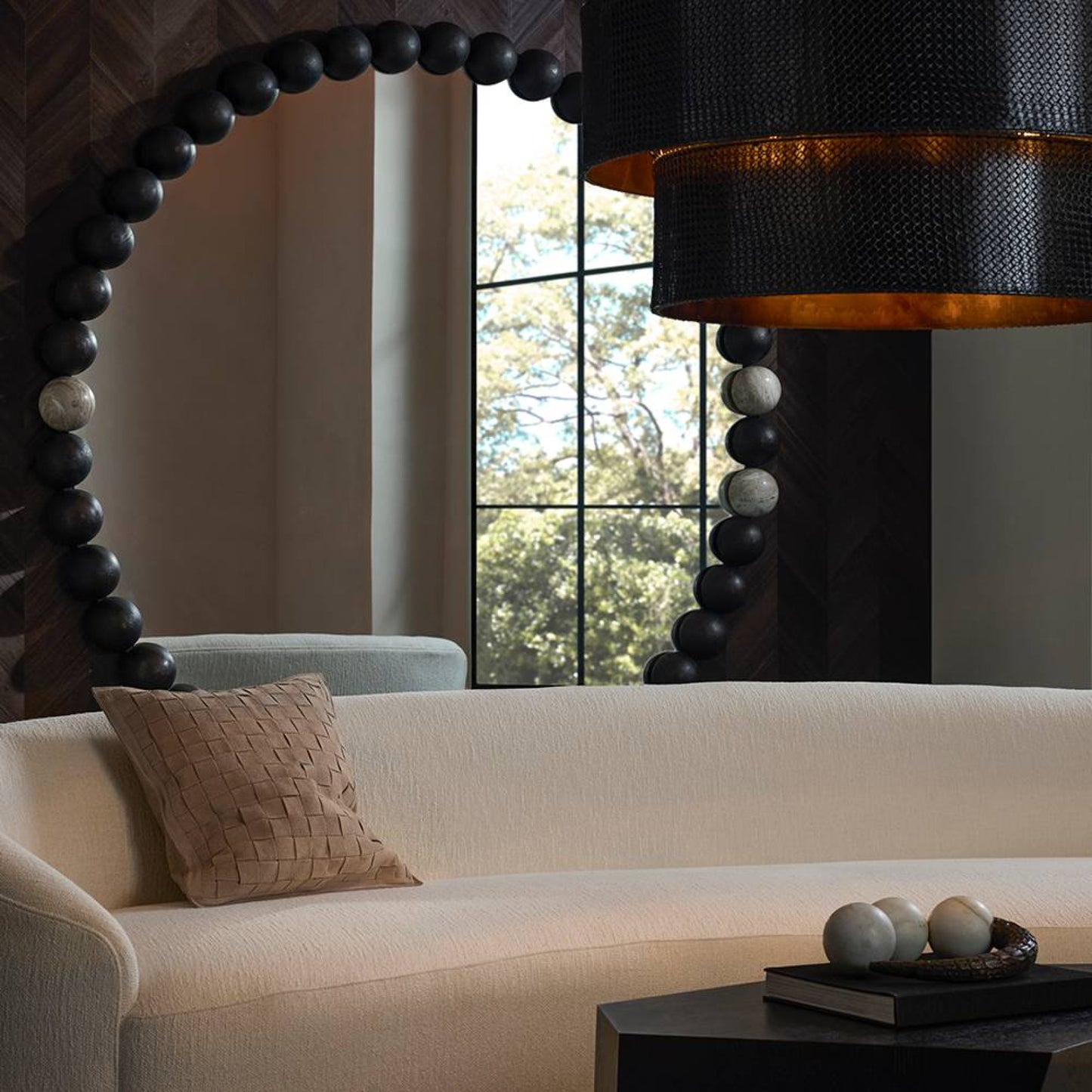 Modern living room with a white sofa, decorative lamp, and large round mirror.