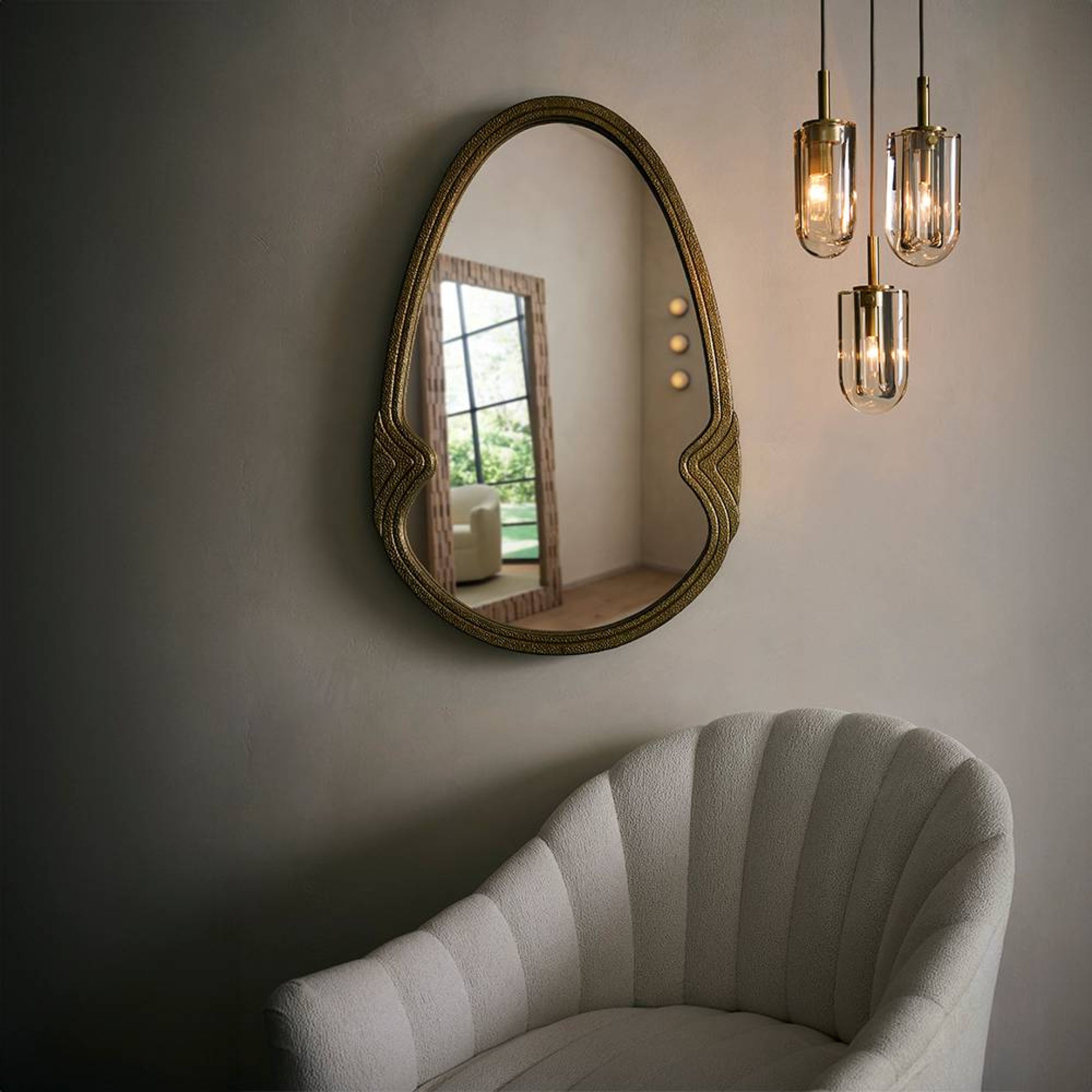 Decorative mirror on a wall with a modern chair and pendant lights in the background.