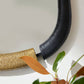 Black flexible duct attached to a gold air filter with leaves in the foreground