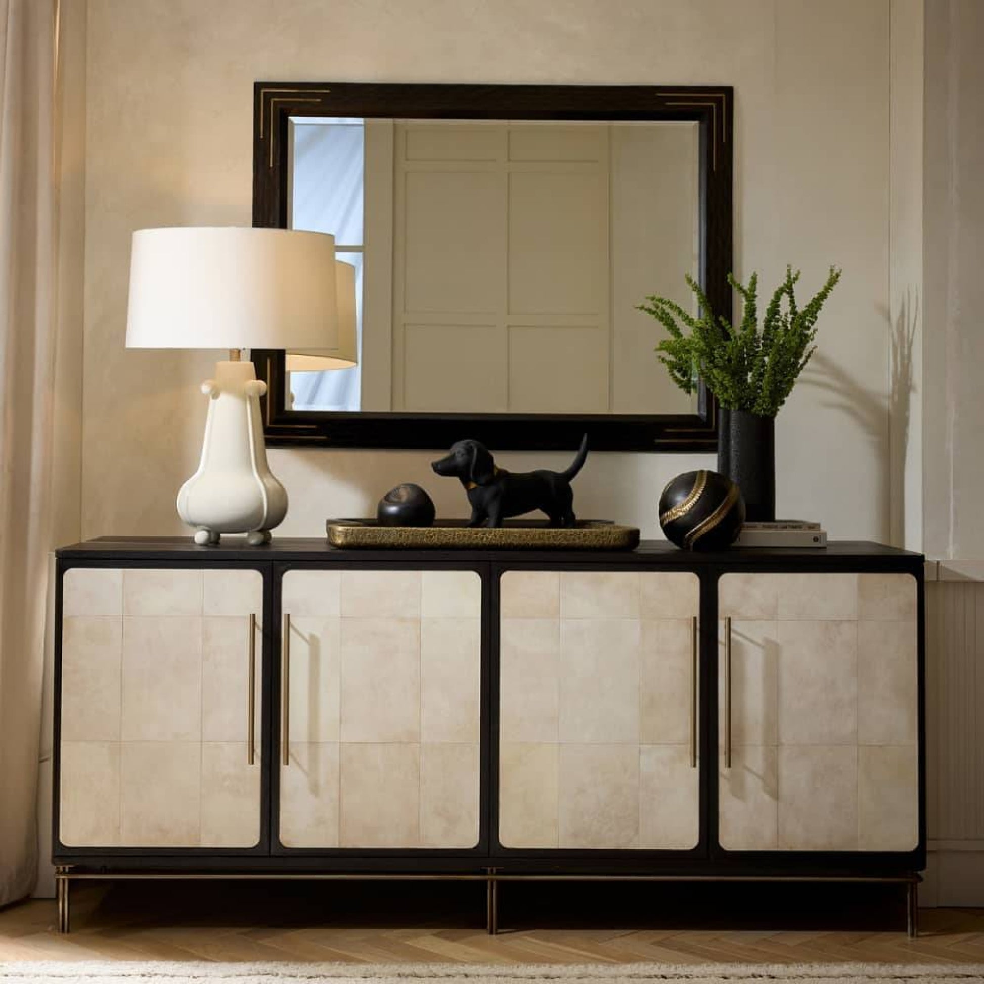 Decorative console table with a lamp, mirror, and decorative items in a room setting.